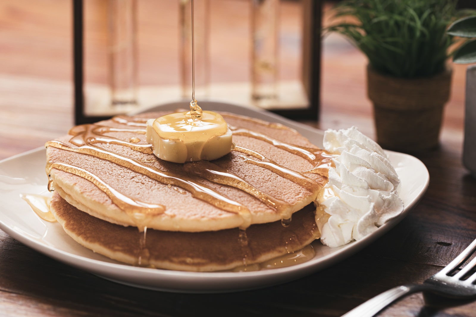 Freshly made pancake with a butter on top and syrup dripping from top